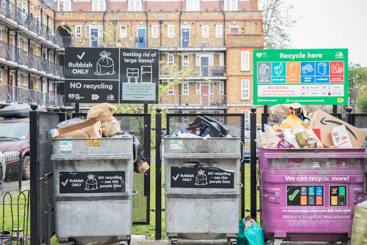 overflowing big bins, blocks of flats in background