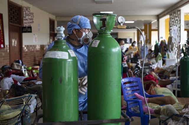 A doctor in front of two oxygen tanks in Iquitos, Peru.