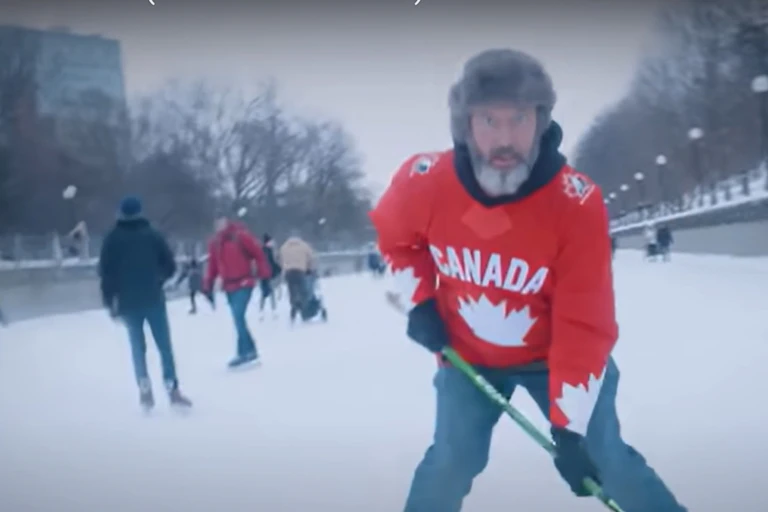 A man in fur hat with a Canada hockey sweater and a hockey stick skating.