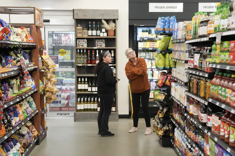 Dos personas miran los productos en el estante para pasar la producción