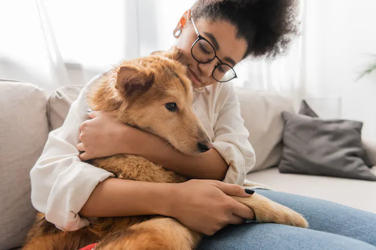 A young woman hugging a dog while sitting on a couch