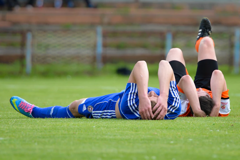 Two young women soccer players hold their heads after a clash