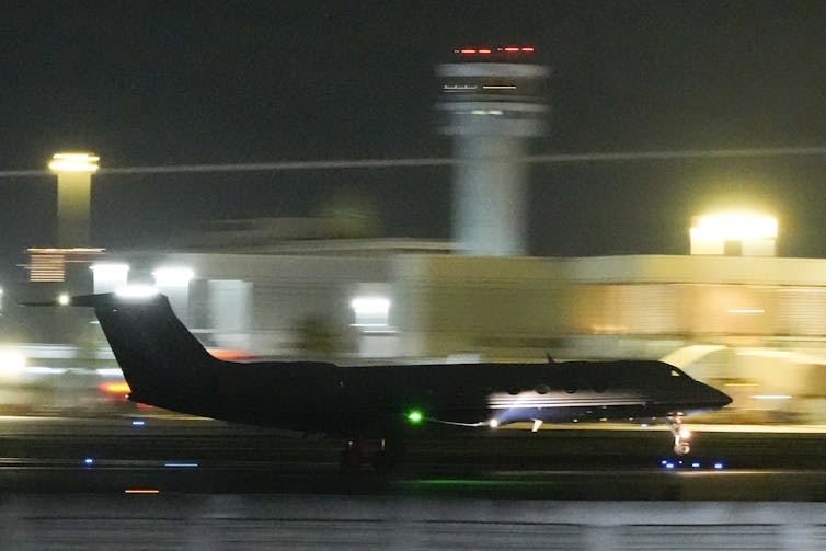 The silhouette of a plane is seen taking off from a runway.