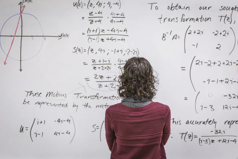 Uma mulher olha para um quadro branco coberto de expressões matemáticas