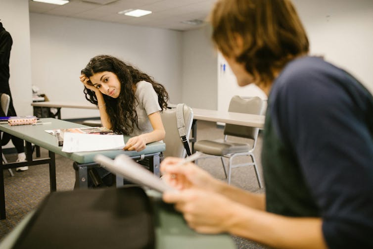 A male students talks to a female student in a classroom.