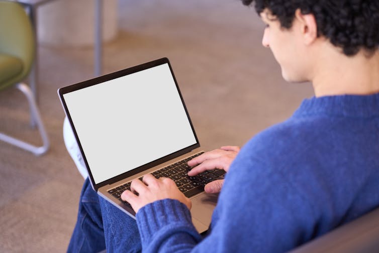 A young man types on a laptop.