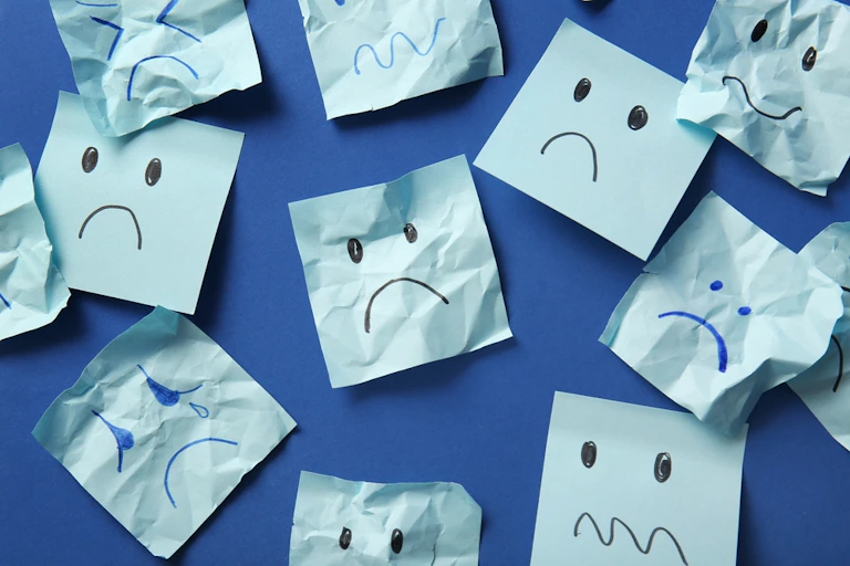 Light blue post-it notes with frowning face on darker blue background