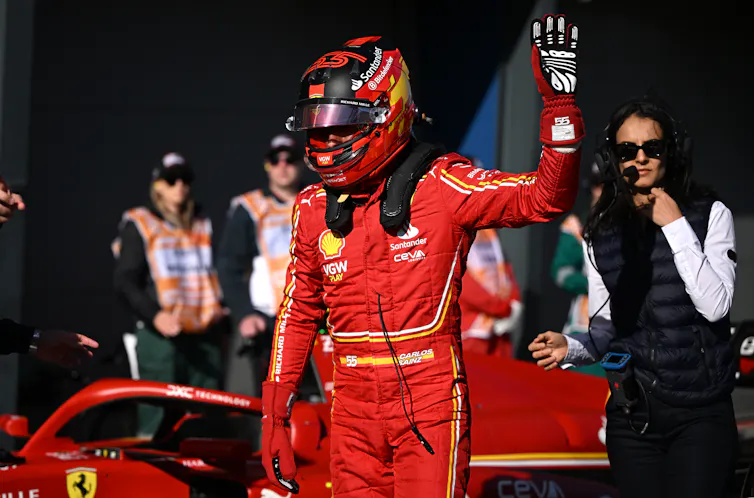 Racecar driver wearing a red suit and a red helmet.