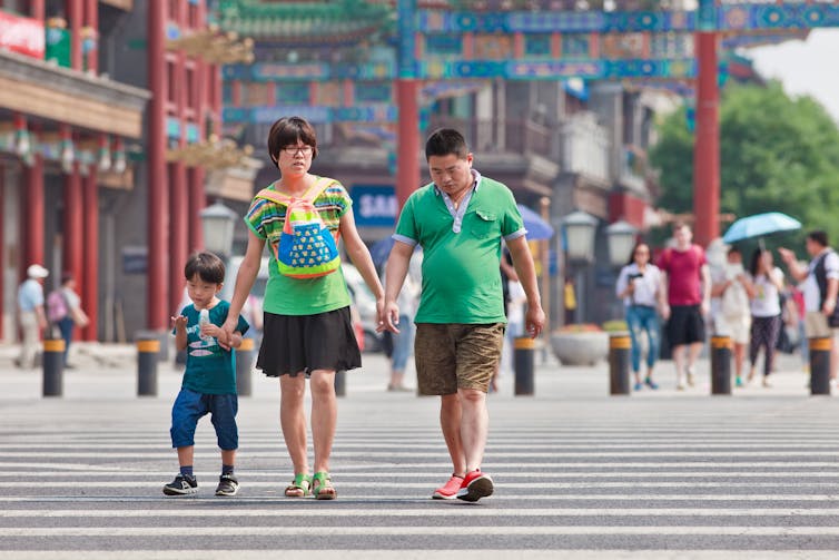 A Chinese couple walk through Beijing with their child.