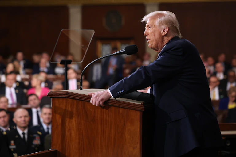 Donald Trump stands at a lectern while addressing a joint sitting of the US Congress.