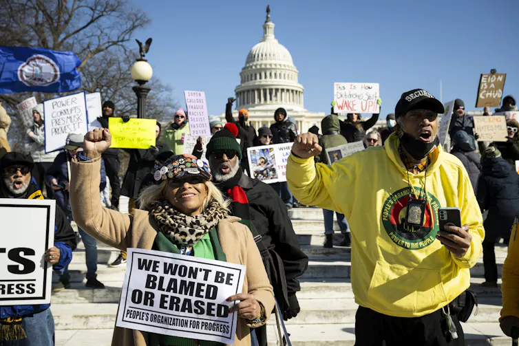 People demonstrate against the Trump administration in Washington, holding up signs to protest against some policies, February 2025