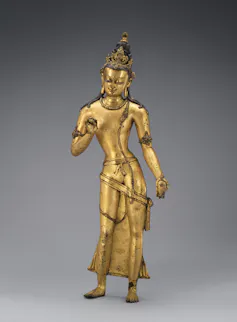 A golden icon of the Bodhisattva Maitreya. He raises one hand with the palm open and holds a flask in the other.
