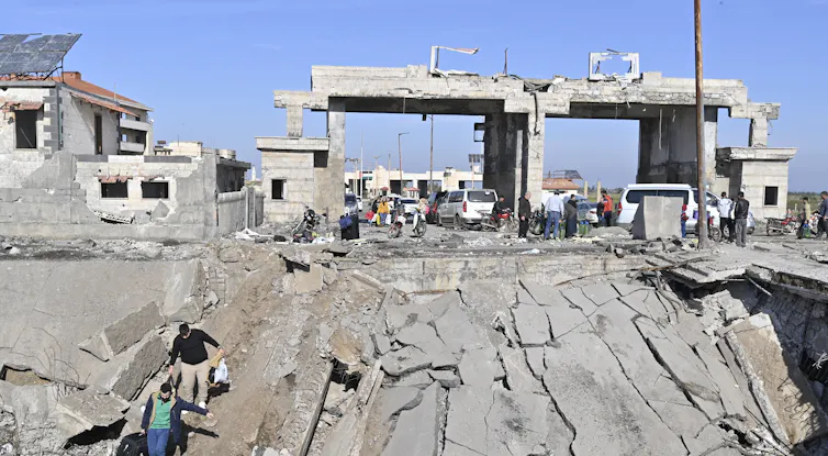 People make there way across a devastated road and bridge carrying belongings.