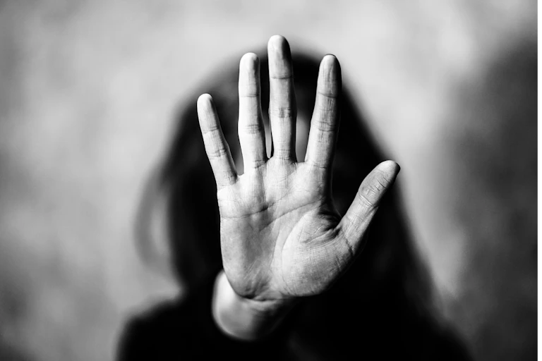 Black and white photo of woman holding her hand up to the camera