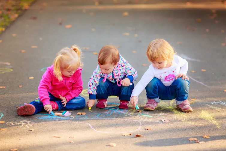 Toddlers drawing on pavement with chalk