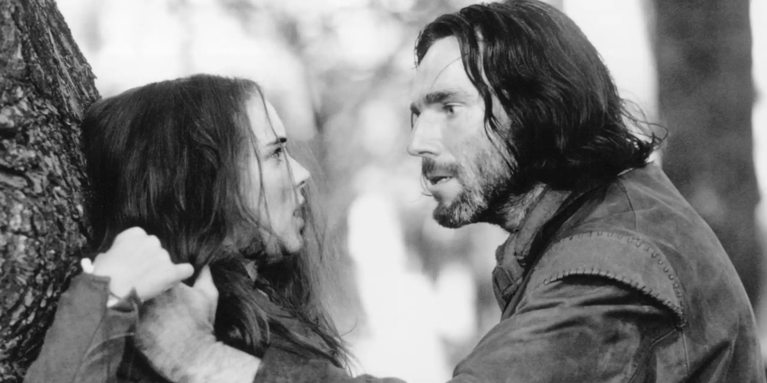 Un hombre sujeta contra un árbol a una mujer.