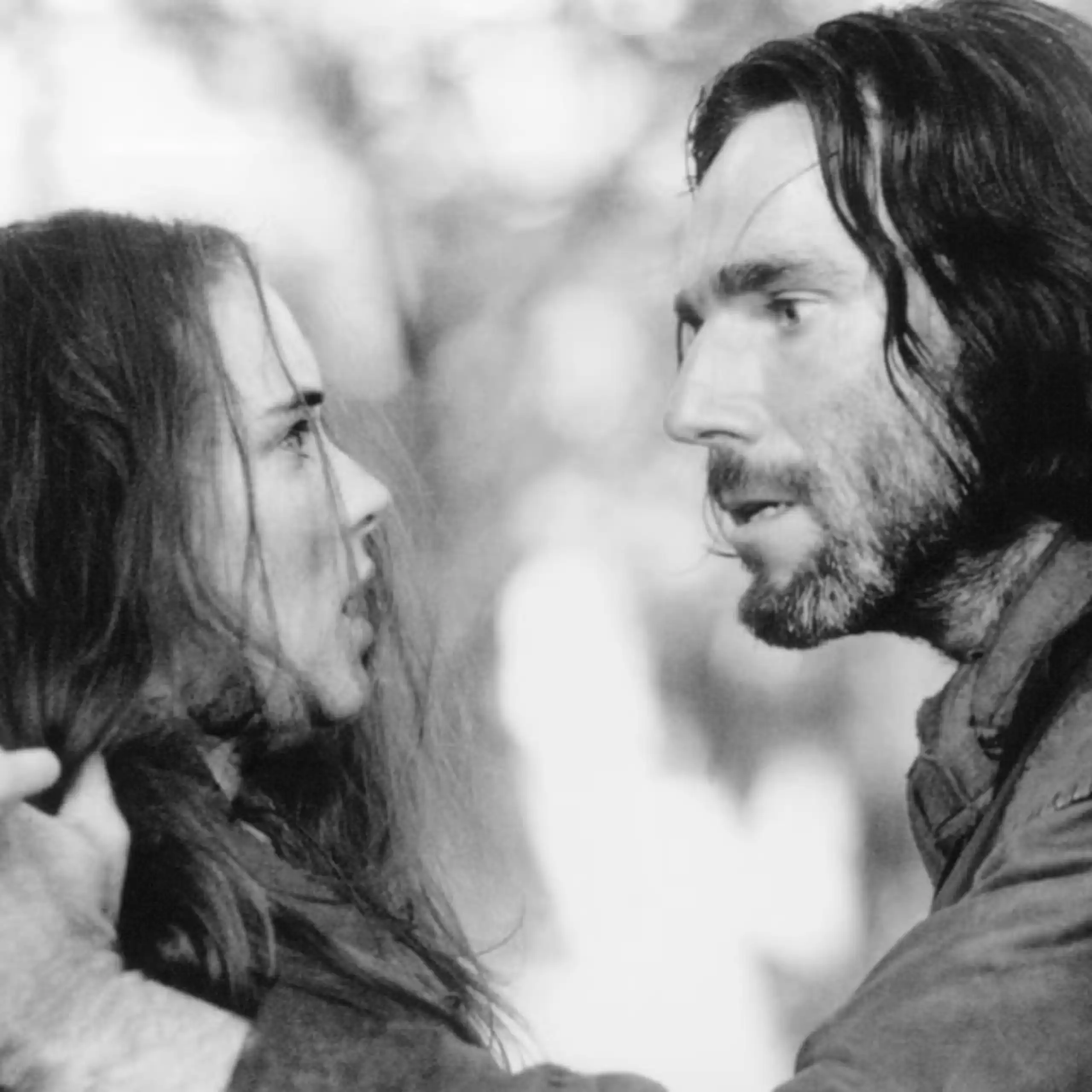 Un hombre sujeta contra un árbol a una mujer.