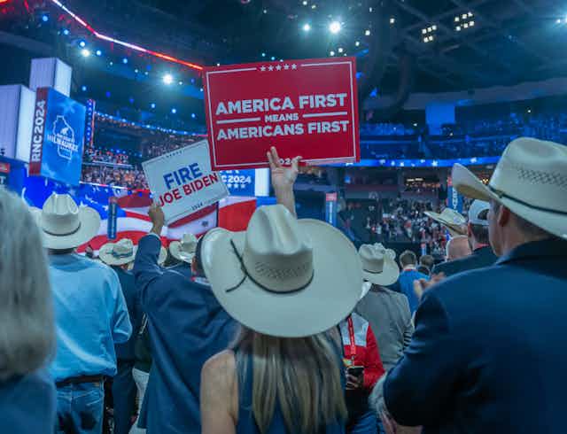 delegates at a trump rally in 2024 hold an America First sign
