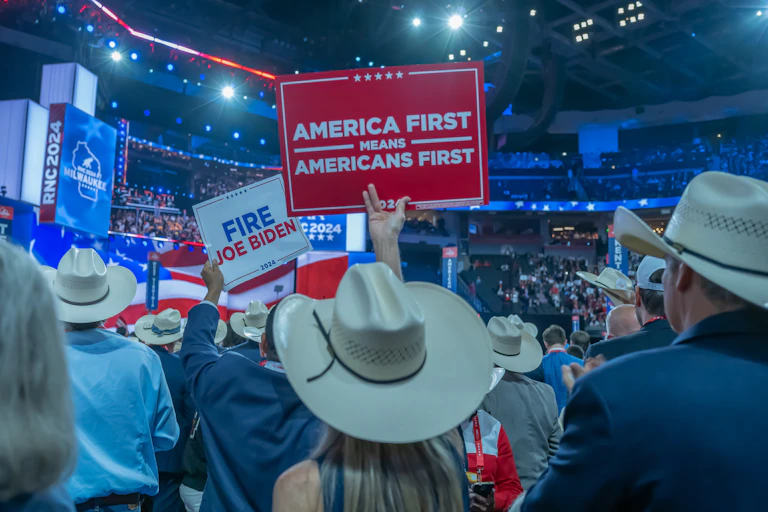 delegates at a trump rally in 2024 hold an America First sign