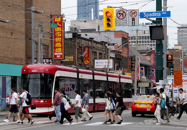 La gente cruza la calle de una concurrida sección transversal de la ciudad frente al tranvía