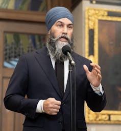 Hombre indio que usa turbante y trajes de la marina hablan en un micrófono
