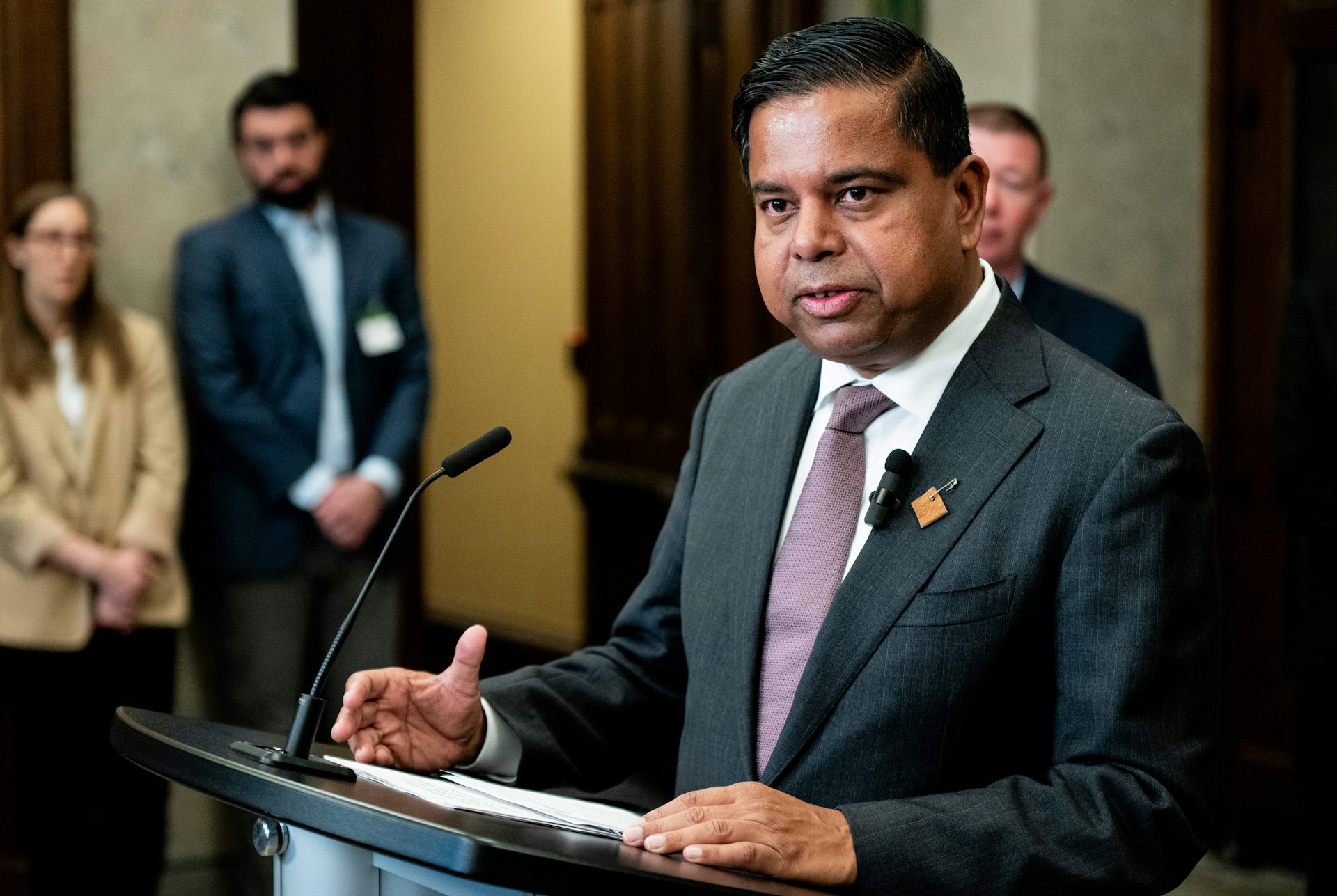 El hombre del sur de Asia en el traje habla en un micrófono detrás del podio