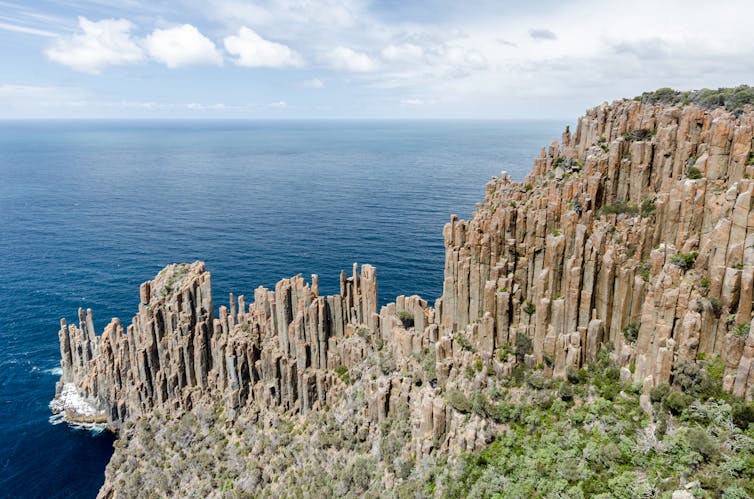 Cliff face with organ pipe-like formations dropping into the ocean.