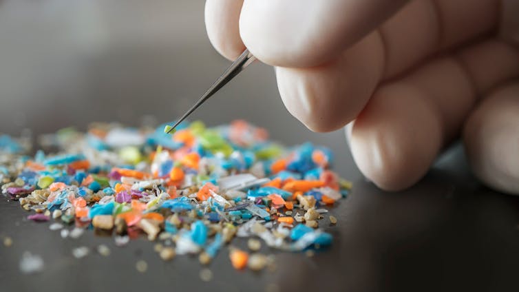 gloved hand picks through microplastic pile