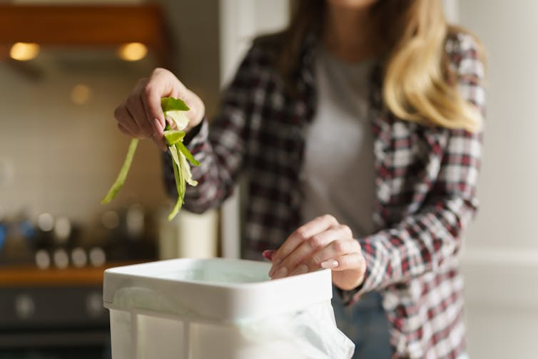 woman places food scraps into bin