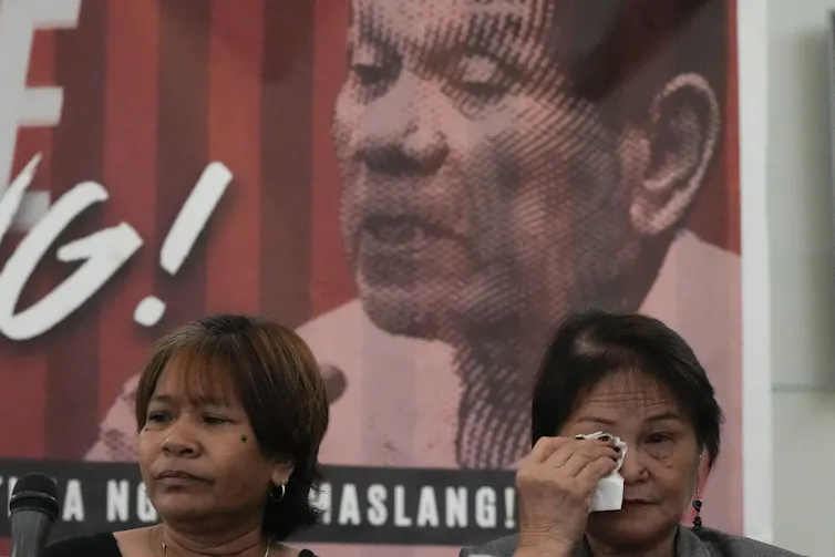 A woman wipes tears from her eyes in front of a portrait of Duterte.