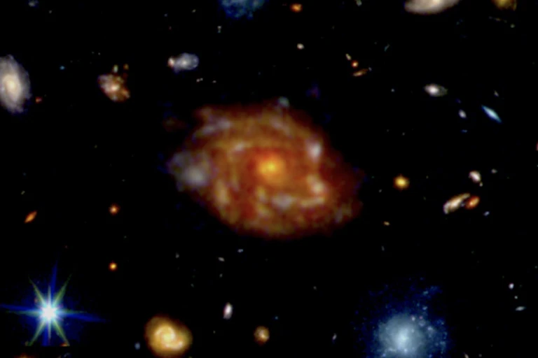 A large orange galaxy with spiral arms and smaller galaxies around it.