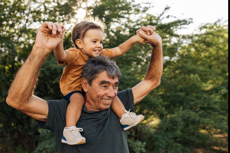 A man with a small child on his shoulders outdoors.