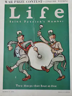 Portada de revista con un dibujo en el que dos hombres desfilan con un bombo ataviados con sombreros altos verdes.