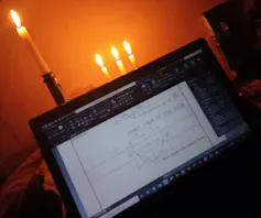 A laptop open and candle in the background.