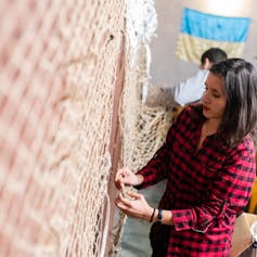 Engineering hope: how I made it my project to lend a hand rebuild Ukraine’s important infrastructure 4 A woman weaving large nets attached to a  wall.
