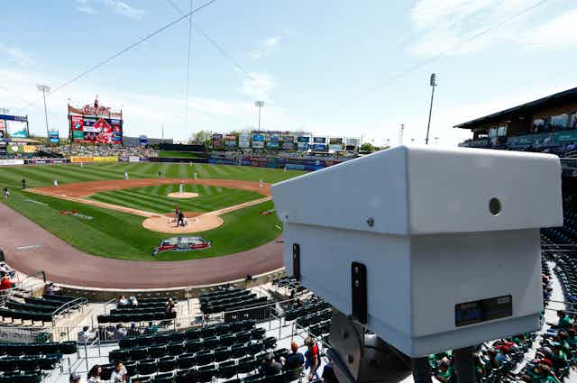 A white camera installed in a baseball stadium overlooking the field.