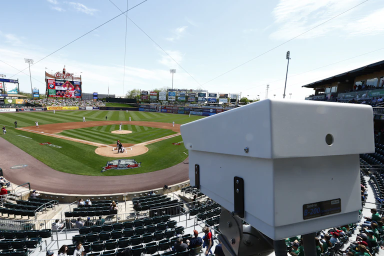 A white camera installed in a baseball stadium overlooking the field.