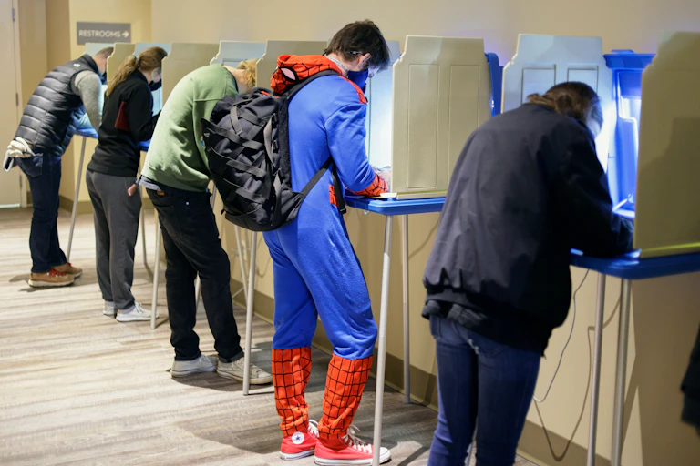 A man dressed as spiderman voting.