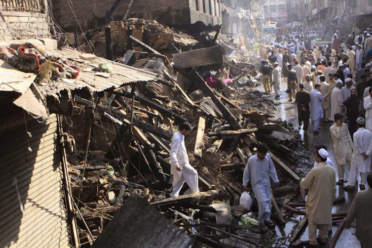 People walk among smoking rubble.