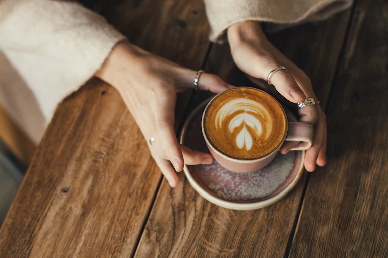 Gros plan sur les mains d’une personne tenant une tasse de café.