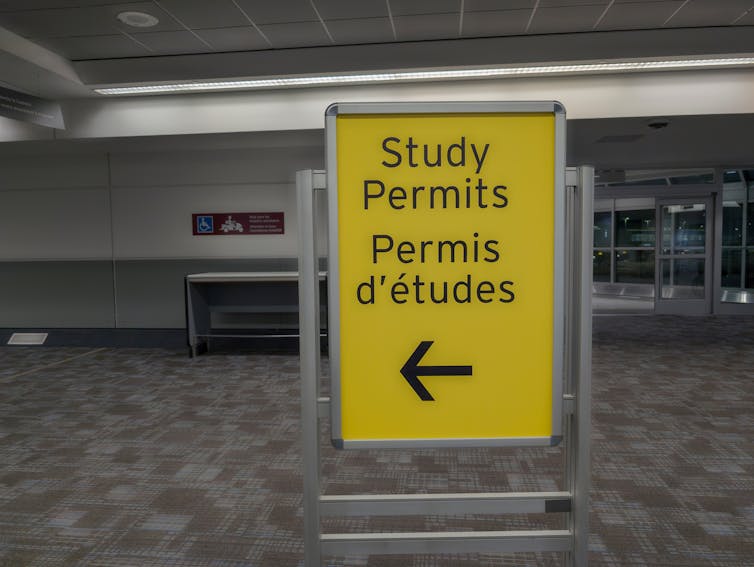 A yellow sign with a bold black arrow, stating 'Study permits' in both English and French.
