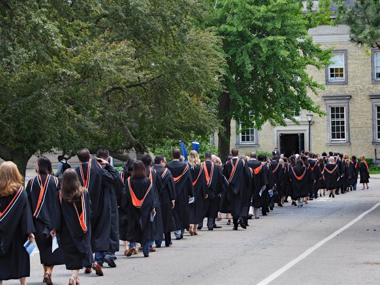 A line of university graduates wearing gowns and caps.