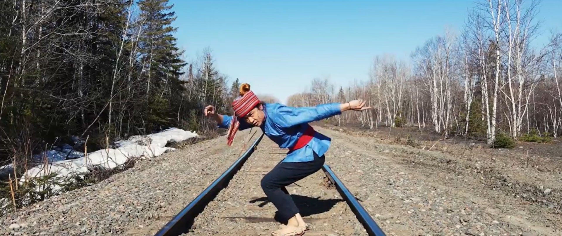 Un homme danse au milieu d'un paysage naturel.