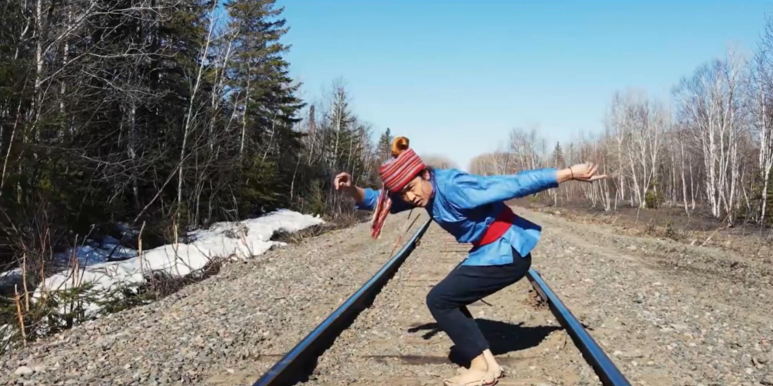 Un homme danse au milieu d'un paysage naturel.