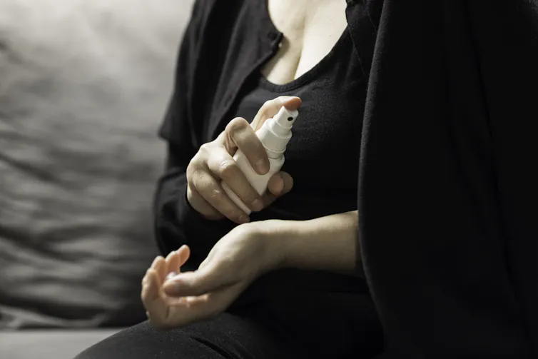 A woman sprays hormone therapy onto the inside of her wrist