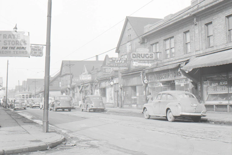A faded image shows classic cars parked on the street in front of stores with signs for "Silver Line Cafe" and "Drugs."