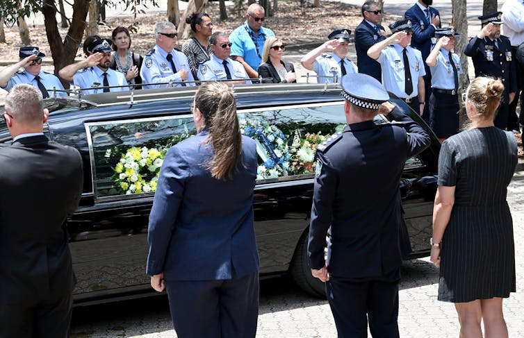 Police guard of honour around a hearse.
