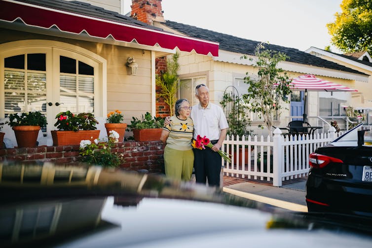 An old man and woman stand outside the suburbs.