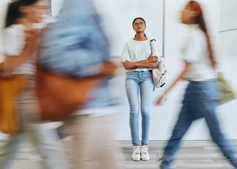 A woman looks concerned and stands still amid a passing crowd
