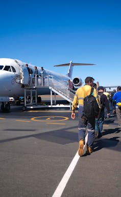 workers in high vis line up for a plane on tarmac
